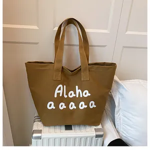 Détail du sac fourre-tout en toile marron avec lettrage blanc et anses en toile robustes