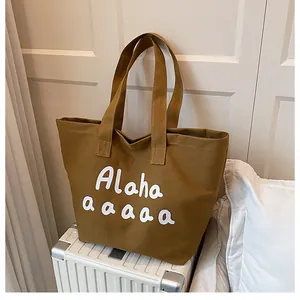 Détail du sac cabas en toile jaune moutarde avec lettrage blanc sur une valise
