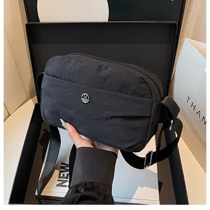 Minimalist black nylon crossbody bag with metal M logo and adjustable shoulder strap