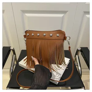 Détail d'un sac bandoulière marron à franges avec clous métalliques argentés