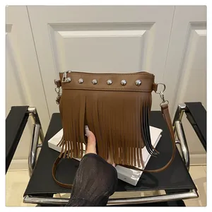 Détail du sac à bandoulière en cuir marron avec rivets argentés et longues franges