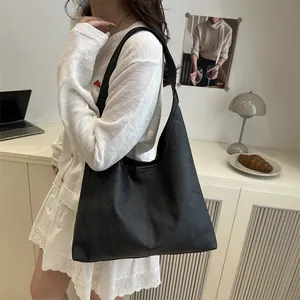 Minimalist black oversized leather tote bag shown in a stylish modern office setting