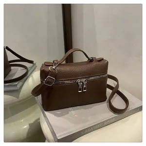 Close-up of brown pebble leather texture and silver dual zippers on the square handbag