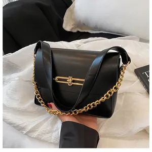 Close-up of the black leather shoulder bag with a gold metal clasp and chain detail