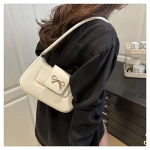 Détail d'un sac baguette blanc avec boucle noeud porté à l'épaule par un mannequin