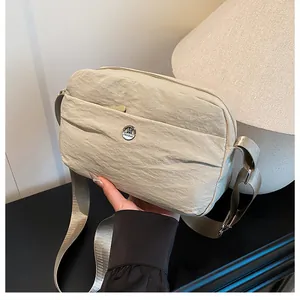 Beige pleated nylon crossbody bag with adjustable shoulder strap and metal M logo