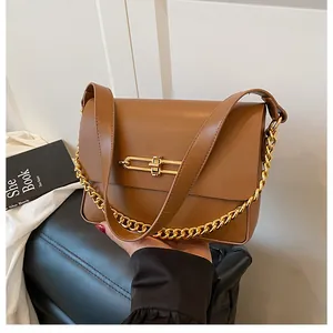 Detail of a brown PU crossbody bag with golden chain and rectangular metal buckle lock