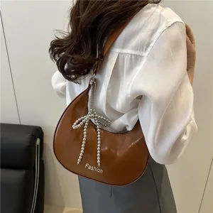 Sac sous-bras demi-lune en cuir marron avec nœud perlé et inscription Fashion