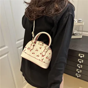 White shell-shaped cherry print handbag with double top handles and gold-tone zippers