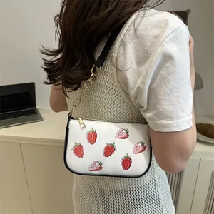 White underarm tote bag with red strawberry print and golden chain strap detail