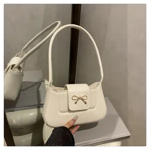 Détail du sac baguette crème avec boucle nœud dorée et texture en cuir lisse