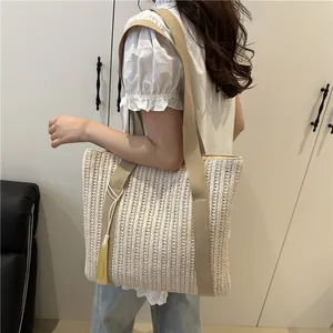 Handwoven cream straw tote bag with wide khaki canvas strap and yellow tassel detail