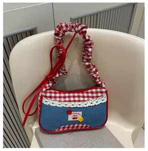Detalle del bolso de retazos en denim azul y cuadros rojos con encaje y bordado de cerezas
