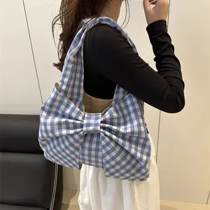 Blue gingham tote bag with large bow detail carried by model in a modern interior