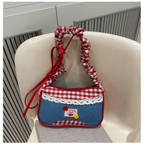Detailed shot of retro blue denim and red gingham handbag with lace trim and cherry embroidery