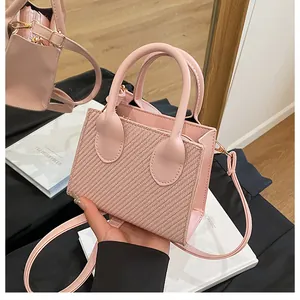 Detail of pink crossbody bag with V-shaped woven texture and gold metal hardware