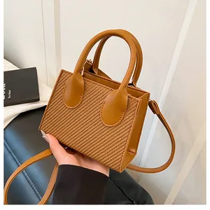 Detail of caramel brown crossbody bag with woven texture and gold hardware accents
