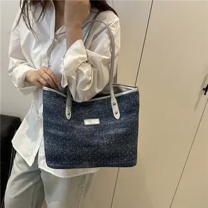 Blue denim tote bag with white polka dots and silver trim shown on model