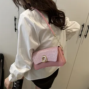 Pink sequin crossbody bag with gold horseshoe buckle and chain strap shown on model