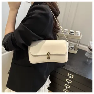 Detail of cream shoulder bag with gold metal buckle on a black blazer outfit