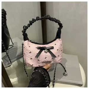 Detail of pink bow handbag with silver heart charm and black ruched leather handle