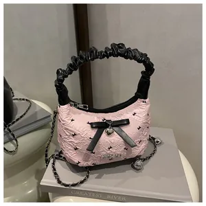 Detail of pink pleated crescent bag with bow decoration and silver heart pendant