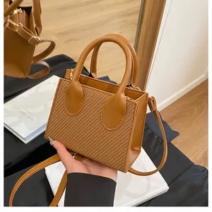 Detail of a brown woven mini tote bag featuring high-quality leather texture and sleek handle