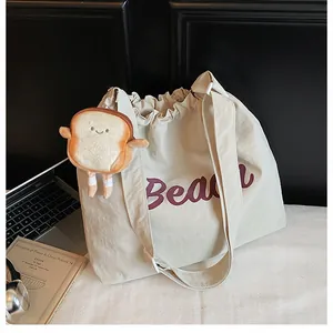 Detail of canvas tote bag featuring Beach print, drawstring closure and toast charm