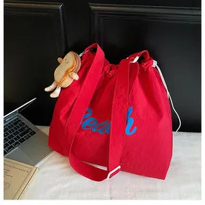 Detail of red nylon tote bag with Peach print, drawstring closure and toast plush pendant