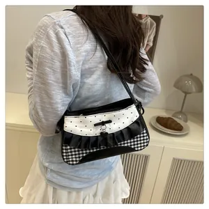 Close-up of heart charm, bow detail and checkered lace texture on the underarm bag
