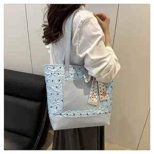Detail of light blue quilted tote bag with black bows and decorative floral silk scarf