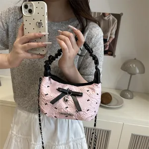 Pink pleated handbag with black bow and heart pendant in a cozy lifestyle setting