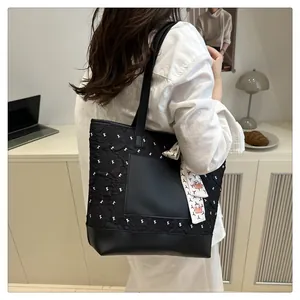 Detail of black quilted tote bag with silk scarf on handle shown in lifestyle setting