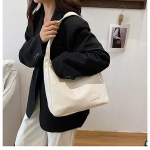 Lifestyle shot of large cream glossy PU leather tote bag worn with a professional outfit