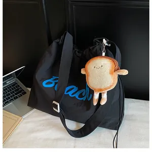 Detail of black nylon tote with blue Beach print and cute plush bread toast charm