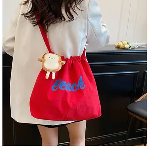 Detail of red drawstring tote bag with blue Beach print and cute toast plush pendant