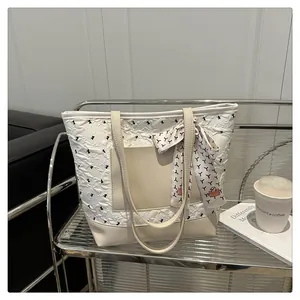 Detail of cream tote bag with pleated texture, leather base and elegant silk scarf accent