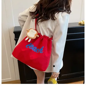 Detail of red drawstring tote bag with Beach embroidery and a cute toast plush charm