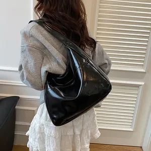 Minimalist large black shiny PU leather tote bag shown on a model in a casual street style