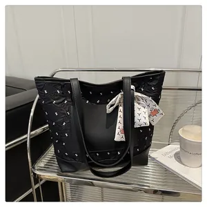 Detail of black tote bag featuring crinkled texture, bow pattern and silk scarf handle decor