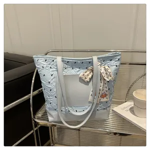 Detail of light blue pleated tote bag with silk scarf and leather trim on silver stand