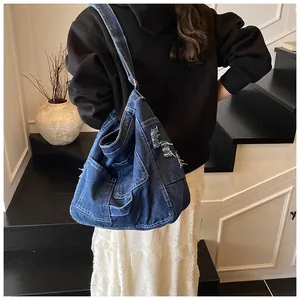 Detail of dark blue denim shoulder bag with vintage frayed pockets and adjustable strap