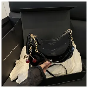 Sac demi-lune en cuir verni noir avec chaîne dorée et bijou cerise dans son coffret