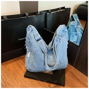 Close-up of denim shoulder bag featuring distressed edges and adjustable metal buckle