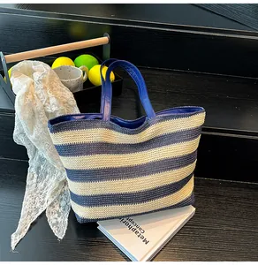 Close-up of woven navy and white striped tote bag with leather-style handles and summer decor