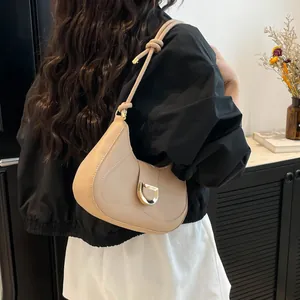 Minimalist beige underarm bag with knot strap and gold D-ring detail on model