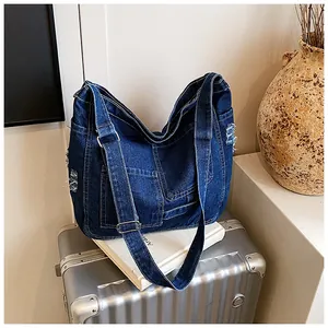 Detail view of denim crossbody bag featuring functional pockets and frayed edges decor