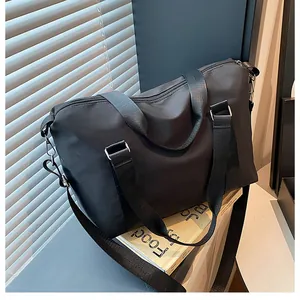 Detailed top view of large black travel bag with shoulder strap and woven handles
