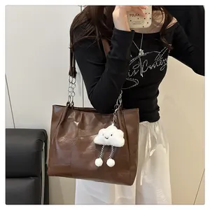 Detail of dark brown tote bag featuring geometric patchwork and cloud plush charm