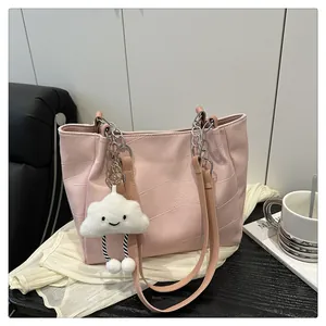 Detail of pink faux leather tote bag with metal chain strap and white plush cloud charm